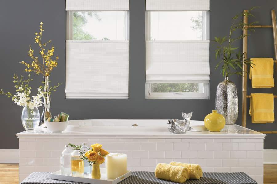 A gray and white bathroom with several yellow decorative objects